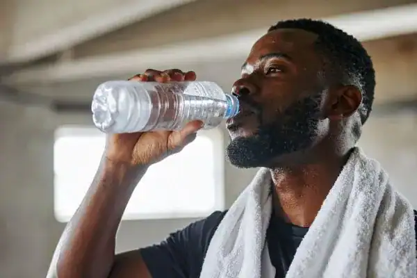 Hydration: The Secret Ingredient for a Toned Stomach and Enhanced Fitness 1 Image of man drinking water to improve hydration Kent after work out.